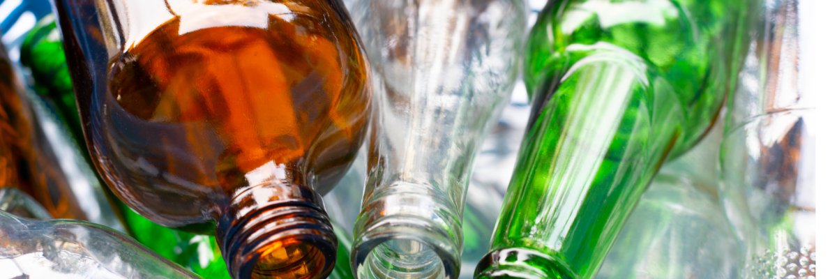 Leere Glasflaschen in verschiedenen Farbtönen liegen nebeneinander.